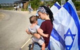 FILE: A woman holds a child during the funeral procession for an IDF soldier, Moshav Avnei Eitan, Golan Heights, July 27, 2025.(Michael Giladi/Flash90)