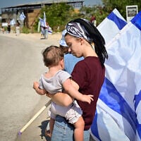 FILE: A woman holds a child during the funeral procession for an IDF soldier, Moshav Avnei Eitan, Golan Heights, July 27, 2025.(Michael Giladi/Flash90)
