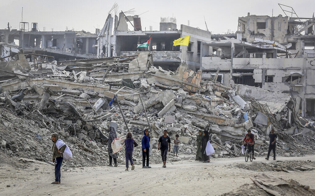 Palestinians walk past buildings destroyed in the recent war, in Khan Younis, in the southern Gaza Strip, November 6, 2025. (Abed Rahim Khatib/Flash90)