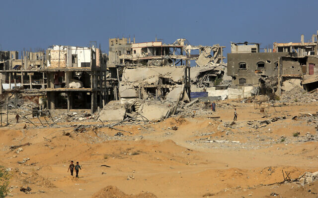 Palestinians walk among destroyed buildings in the eastern part of Khan Younis, in the southern Gaza Strip, November 12, 2025. (Abed Rahim Khatib/Flash90)