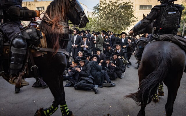 Haredi men block the road outside the IDF recruitment center in Jerusalem on November 12, 2025 (Chaim Goldberg/Flash90)