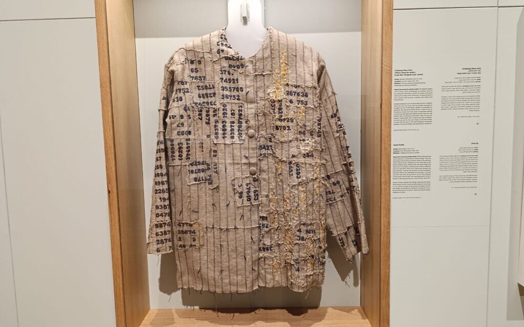 An artistic rendition by Holocaust survivor Shulamit Levin of the biblical Joseph’s coat of many colors reimagined as a frayed prisoner’s shirt scarred with identification numbers and flower petals. Displayed in Yad Vashem's Living Memory exhibition (Zev Stub/Times of Israel)