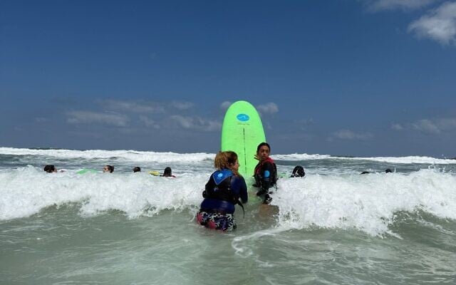 Women from Kibbutz Nir Oz close to the Gaza border meet with HaGal Sheli for a surfing lesson on the Ashkelon coast, September 3, 2025. (Courtesy of HaGal Sheli)