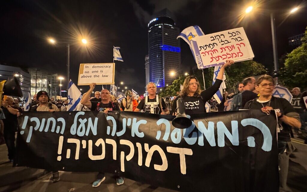 Anti-government protesters march in Tel Aviv, carrying a manner reading, "The government isn't above the law. Democracy!" on November 15, 2025. (Vardit Alon-Korpel/Pro-Democracy Protest Movement)