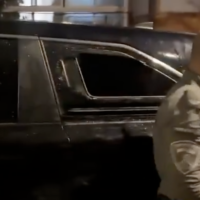 A police officer stands next to a broken car window in footage of the mob attack on Shas MK Yoav Ben-Tzur's car in the Jerusalem area, November 15, 2025. (Screenshot from X)