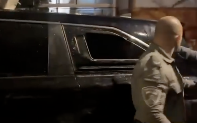 A police officer stands next to a broken car window in footage of the mob attack on Shas MK Yoav Ben-Tzur's car in the Jerusalem area, November 15, 2025. (Screenshot from X)