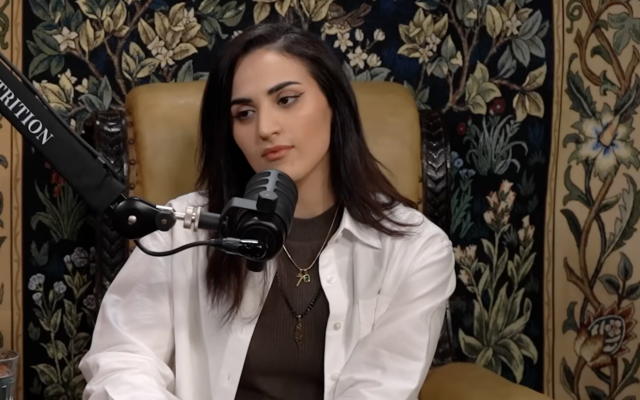 Dr. Rahmeh Aladwan, who's had her medical registration suspended for 15 months over antisemitic social media posts, speaks to an interviewer. She is wearing an "O7" necklace alluding to Hamas's Oct. 7 attack. (Screen capture via ATTRITION podcast on YouTube)