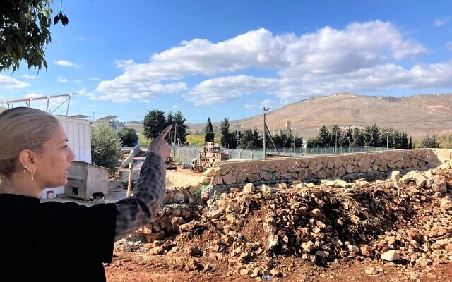 On her backyard terrace in Avivim, Limor Biton points to a hill in Lebanon and Bint Jbeil, a Hezbollah stronghold, on November 26, 2025. (Diana Bletter/Times of Israel)