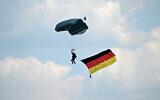 Illustrative: A paratrooper of the German armed forces Bundeswehr is seen with a German flag in the sky over the military base of Kaufbeuren, southern Germany, during an Open Day of the Bundeswehr, on June 17, 2023. (Christof STACHE / AFP)