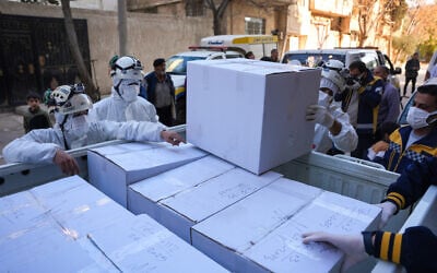 Members of Syria's White Helmets civil defense service load boxes containing the remains of people found in the basement of a building in the city of al-Sbaynah, southwest of Damascus, on January 29, 2025. (Rami al SAYED / AFP)