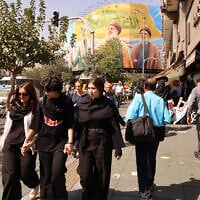 Iranian women walk in front of a billboard depicting slain Hezbollah leader Hassan Nasrallah (C) and his successor Hashem Safieddine (R) as well as the late Iranian General Qasem Soleimani, in Tehran on September 28, 2025.(Atta Kenare/AFP)