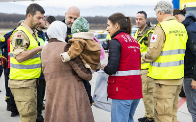 A woman with her baby disembark after landing to Geneva Airport, in Geneva, for medical treatment, on November 28, 2025. (SALVATORE DI NOLFI / POOL / AFP)