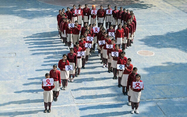 School girls pose with placards as they align in a formation of the red ribbon to raise awareness on 'World AIDS Day' in Amritsar, India, on December 1, 2025. (Narinder NANU / AFP)