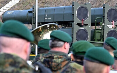German soldiers play in a military brass band in front of the Arrow 3 shield system during an event of the German Air Force to declare the Initial Operating Capability for the Arrow Weapon System for Germany at the Annaburger Heide Air Base in Schoenewalde/Holzdorf, eastern Germany, December 3, 2025 (Ralf Hirschberger/AFP)