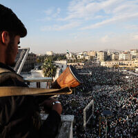 A member of the Syrian security forces stands guard from a position overlooking crowds during celebrations marking one year since a lightning Islamist-led offensive that eventually toppled the country's longtime ruler Bashar al-Assad, in central Hama on December 5, 2025. (OMAR HAJ KADOUR / AFP)