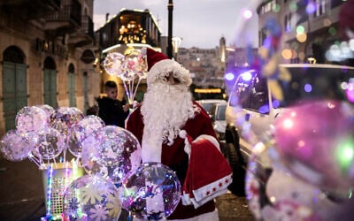 A man dressed as Santa Claus sells balloons near Nativity Square during a Christmas tree lighting ceremony in Bethlehem, in the West Bank, on December 6, 2025. (Photo by JOHN WESSELS / AFP)