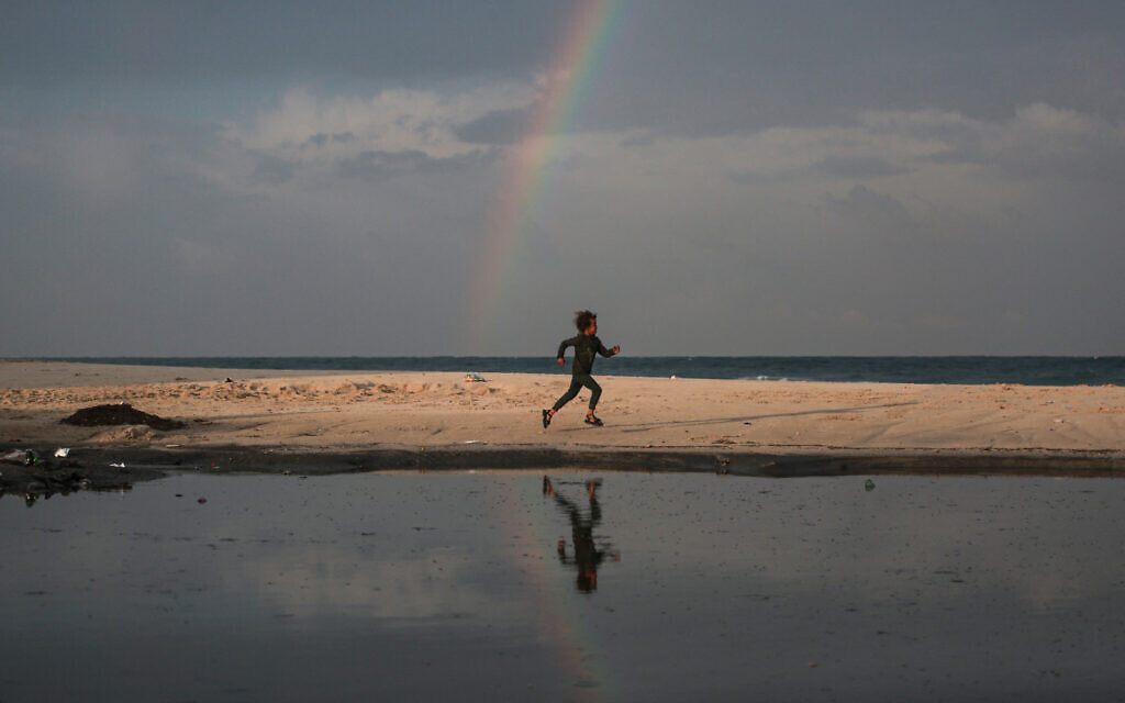 A child runs along the beach as a rainbow emerges over Deir al-Balah, in the central Gaza Strip, on December 10, 2025. (BASHAR TALEB / AFP) A child runs along the beach as a rainbow emerges over Deir al-Balah, in the central Gaza Strip, on December 10, 2025. (BASHAR TALEB / AFP)