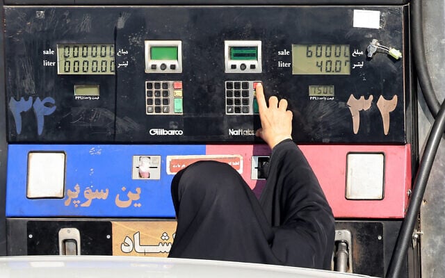 زنی در حال سوخت‌گیری خودروی خود در پمپ بنزینی در تهران، ایران، ۱۳ دسامبر ۲۰۲۵.