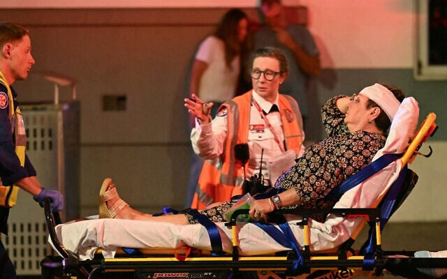 Health workers move a woman on a stretcher to an ambulance after a deadly terror shooting at Bondi Beach in Sydney on December 14, 2025. (Saeed KHAN / AFP)