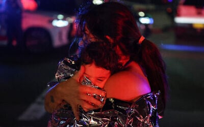 A woman holds her child after a deadly terror shooting at a Hanukkah event at Sydney's Bondi Beach on December 14, 2025. (DAVID GRAY / AFP)