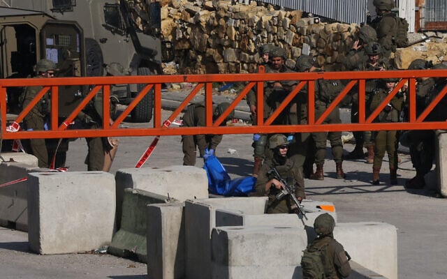 Israeli security forces move a blue body bag after a Palestinian man, who allegedly tried to stab soldiers, was shot and killed at the north entrance of the West Bank city of Hebron on December 14, 2025. (Hazem Bader/AFP) Israeli security forces move a blue body bag after a Palestinian man, who allegedly tried to stab soldiers, was shot and killed at the north entrance of the West Bank city of Hebron on December 14, 2025. (Hazem Bader/AFP)