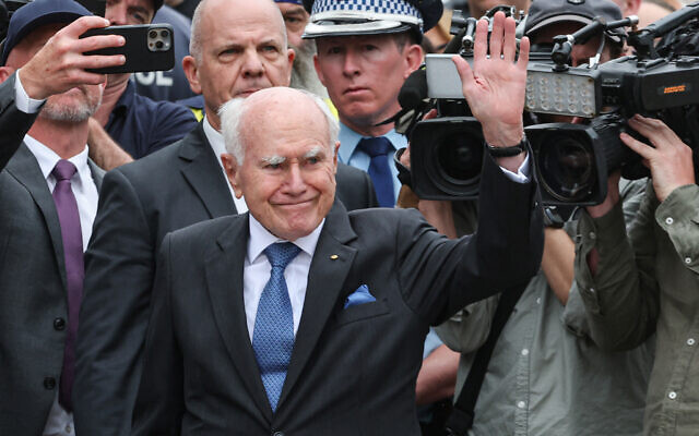 John Howard (C), former prime minister of Australia, waves to the crowd after laying flowers outside Bondi Pavilion in Sydney on December 16, 2025, to honor victims of the Hanukkah terror attack (DAVID GRAY / AFP)