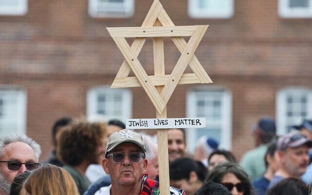 A mourner holds up a wooden Star of David with a sign reading 'Jewish Lives Matter' as people gather around floral tributes outside Bondi Pavilion in Sydney on December 16, 2025. (DAVID GRAY / AFP) A mourner holds up a wooden Star of David with a sign reading 'Jewish Lives Matter' as people gather around floral tributes outside Bondi Pavilion in Sydney on December 16, 2025. (DAVID GRAY / AFP)