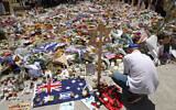 A mourner lights candles as people gather around floral tributes outside Bondi Pavilion in Sydney on December 17, 2025, to honor victims of the Bondi Beach Hanukkah shooting (DAVID GRAY / AFP)