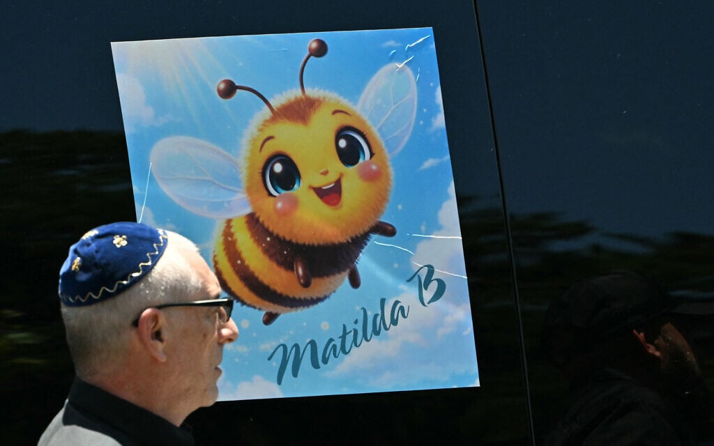 A bee sticker referencing 10-year-old Matilda, who was killed in the Bondi Beach terror attack, is displayed on a vehicle as a mourner walks past after her funeral service in Sydney on December 18, 2025. (Saeed Khan/AFP)