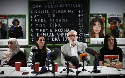 Jeremy Corbyn, center, with other supporters of prisoners being held on charges related to the banned Palestine Action group, in London on December 18, 2025. The names and photos of the hunger strikers can be seen from behind. (Henry Nicholls/AFP)