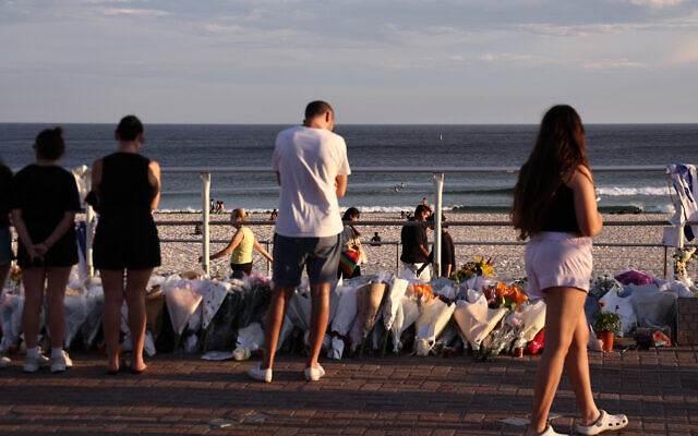 Mourners look at flowers laid next to the beach in memory of victims of a terror shooting targeting a Jewish event days earlier, at Bondi Beach, in Sydney, Australia, on December 20, 2025. (DAVID GRAY / AFP)