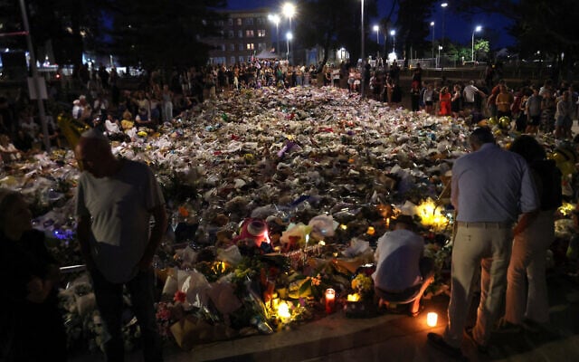 Mourners gather next to floral tributes laid in memory of the victims of a terror shooting targeting a Jewish event at Bondi Beach, in Sydney, on December 20, 2025. (DAVID GRAY / AFP)