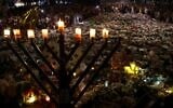 A menorah is pictured after the seventh candle is lit for the Jewish festival of Hanukkah as mourners stand next to floral tributes laid out in memory of the victims of a shooting attack at Bondi Beach, in Sydney, December 20, 2025. (David Gray / AFP)