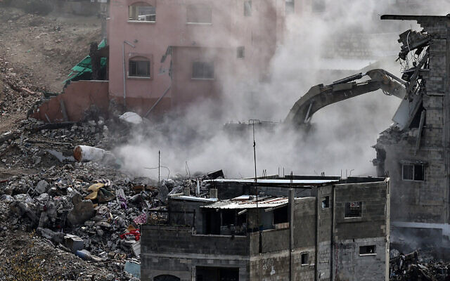 An Israeli military excavator tears down one of 25 residential buildings earmarked for demolition in the Nur Shams camp Palestinian refugees east of the northern West Bank city of Tulkarem, amid an ongoing offensive on December 31, 2025. (Photo by Zain JAAFAR / AFP)