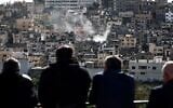 Residents of the Nur Shams Palestinian refugee camp watch their homes being demolished on New Year's eve by an Israeli military excavator in the Nur Shams camp, east of the northern West Bank city of Tulkarem, amid an ongoing offensives in the West Bank on December 31, 2025. (Photo by Zain JAAFAR / AFP)
