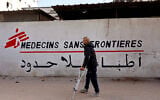 A Palestinian man walks on his crutches to the Doctors Without Borders or Medecins Sans Frontieres (MSF) clinic, in the al-Rimal neighborhood of Gaza City on New Year's Eve, December 31, 2025. (Omar AL-QATTAA / AFP)