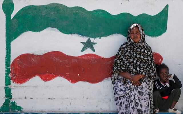 A woman and child relax next to a mural of Somaliland's flag, in Hargeisa, Somaliland, a semi-autonomous breakaway region of Somalia, on February 9, 2022. (AP Photo/Brian Inganga)