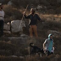 Israeli settlers walk down a hill as Israeli soldiers block access for Palestinians to an area for harvesting olives in the West Bank village of Sa'ir, near Hebron, October 23, 2025. (Leo Correa/AP)