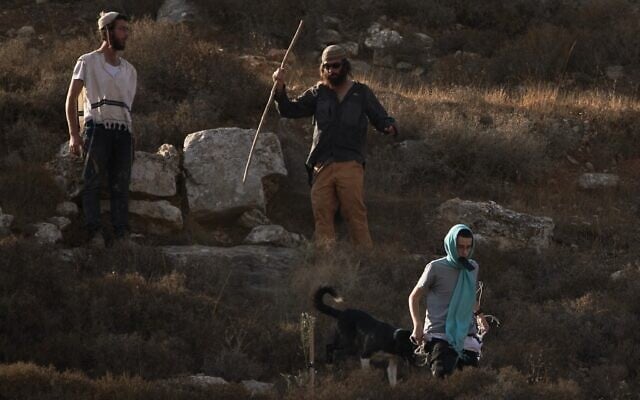 Colonos israelíes caminan por una colina mientras soldados israelíes bloquean el acceso de los palestinos a una zona de recolección de aceitunas en la aldea cisjordana de Sa'ir, cerca de Hebrón, el 23 de octubre de 2025. (Leo Correa/AP)