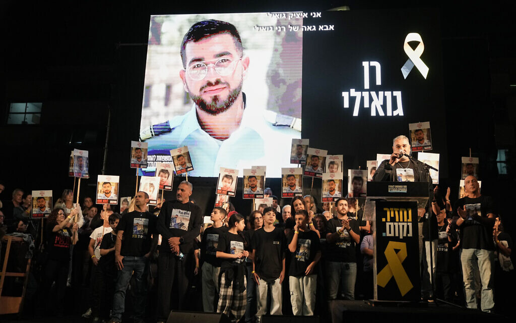 A photo of slain hostage Ran Gvili, whose remains are being held by Hamas in the Gaza Strip, is displayed as his father Itzik speaks during a rally at Hostages Square in Tel Aviv, November 29, 2025. (AP Photo/Mahmoud Illean)