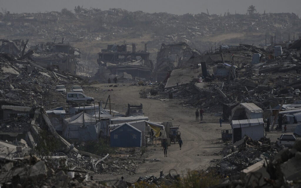Palestinians walk through the destruction in Gaza City, December 5, 2025. (AP/Abdel Kareem Hana) Palestinians walk through the destruction in Gaza City, December 5, 2025. (AP/Abdel Kareem Hana)