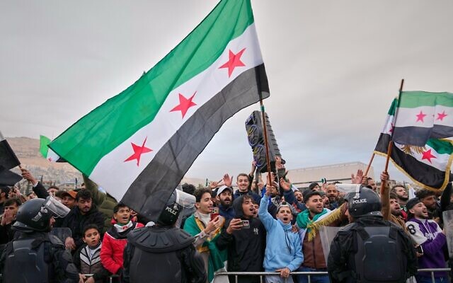 Syrians line the streets awaiting a parade by the new Syrian army marking the first anniversary of the ousting of the Bashar Assad regime in Damascus, Syria, Dec. 8, 2025. (AP Photo/Hussein Malla)