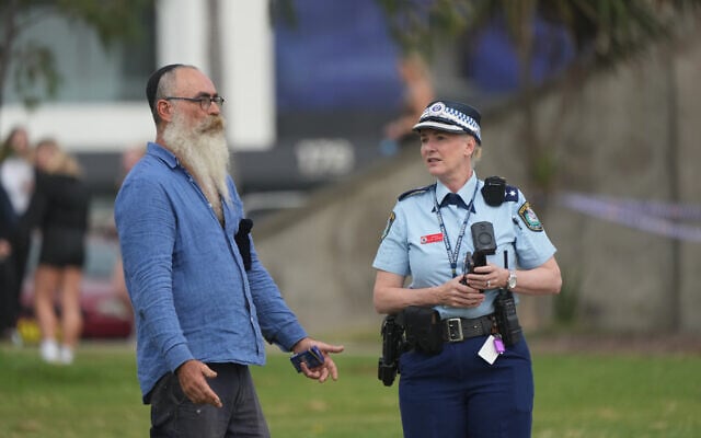 A police officer talks to a member of the public, following a shooting the day prior at Sydney's Bondi Beach, December 15, 2025. (AP/Mark Baker) A police officer talks to a member of the public, following a shooting the day prior at Sydney's Bondi Beach, December 15, 2025. (AP/Mark Baker)