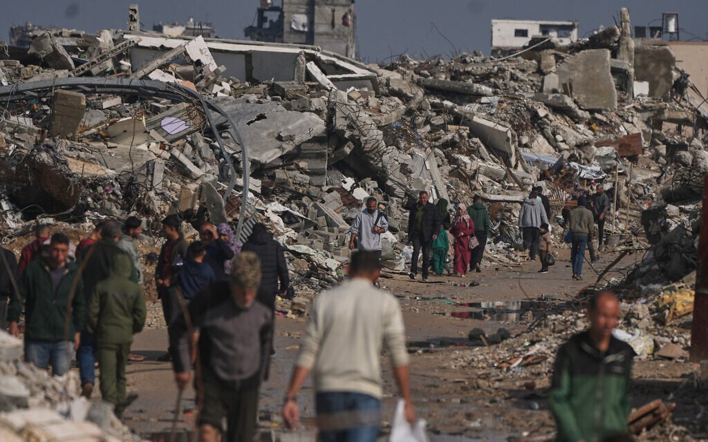 Palestinians walk along a street surrounded by buildings destroyed during Israeli air and ground operations in Gaza City, December 17, 2025. (AP Photo/Jehad Alshrafi)