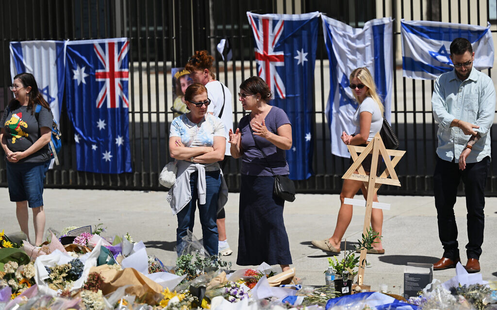 People stand near a floral tribute outside Bondi Pavilion at Bondi Beach in Sydney, Thursday, Dec. 18, 2025. (AP/Steve Markham)