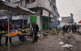 Palestinians walk along street market where fruits and vegetables are displayed for sale in Gaza City, Friday, Dec. 19, 2025. (AP Photo/Abdel Kareem Hana)