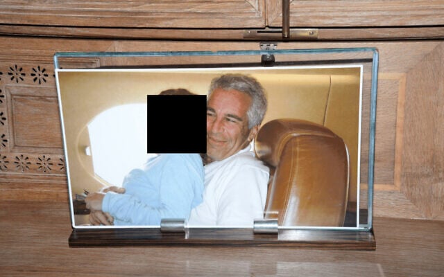 This redacted photo released by the US Department of Justice shows a framed photograph of Jeffrey Epstein with a person on his lap, documented on August 12, 2019, during a search of his home on Little St. James island in the US Virgin Islands. (US Department of Justice via AP)
