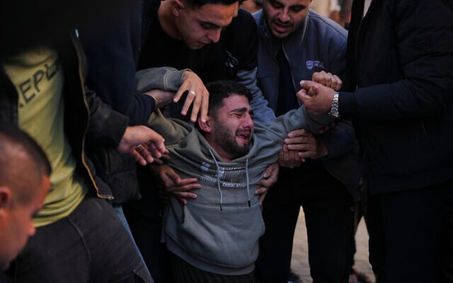 Mohammed al-Neder, 21, mourns over the bodies of members of his family, who were reportedly killed by Israeli fire on a school-turned-shelter in the Tuffah neighborhood of Gaza City, December 20, 2025. (AP/Abdel Kareem Hana)