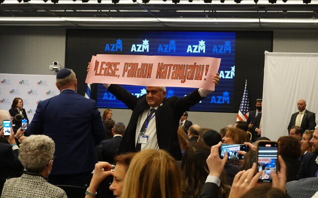 An audience member demands President Isaac Herzog pardon Prime Minister Netanyahu at an American Zionist Movement event in New York City, December 8, 2025. (Luke Tress/Times of Israel)