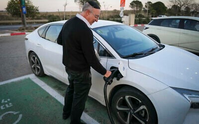 A man recharges his electric car at a charging station in Katzrin in the Golan Heights, January 21, 2025. (Michael Giladi/Flash90)